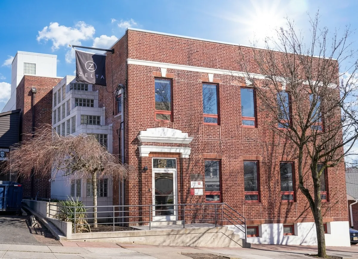 Zelta Design’s brick office building at 139 Chestnut Street in Nutley, New Jersey, with the company flag beside the entrance.